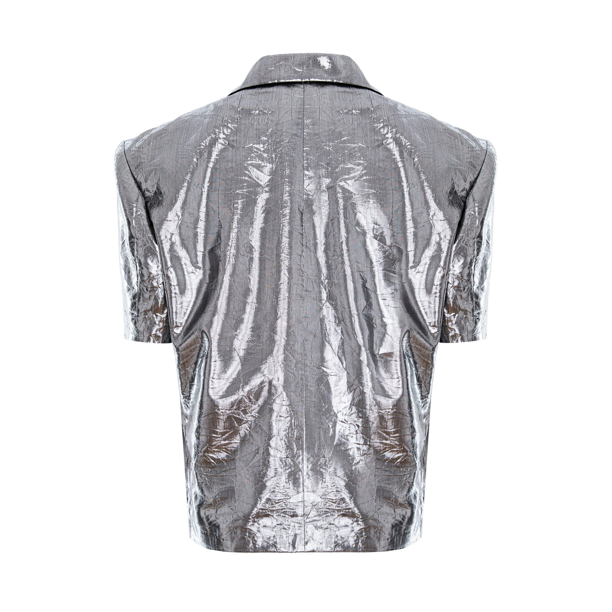 A metallic silver short-sleeve button-up shirt shown from the back, featuring a highly reflective, crinkled texture and a pointed collar, set against a plain white background.